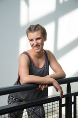 Smiling young woman in boxer braids resting after workout in urban location, wearing sporty outfit.