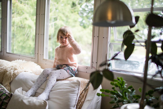 Young girl sitting on couch touching her hair