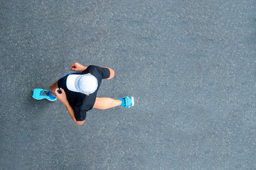 Man sprinting in the morning outdoors. Top view of male runner working out in the city.