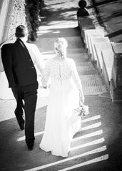 Ein Brautpaar schreitet eine Treppe hinunter. Schwarz/Weiß Aufnahme