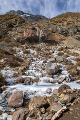 Fototapeta na wymiar Andes mountains inside central Chile an amazing rugged landscape with steep rock faces and an awe scenery with a frozen river icefall and snowcapped mountains inside a wild environment