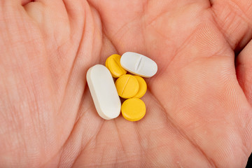 Men's hand with a few pills. Medical drugs for the treatment of various diseases.