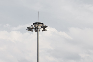 Lighting pole with halogen floodlight and  lightning conductor on the top of it. Metal construction with illuminator. Lighting coverage of a large area. City and urban illumination.