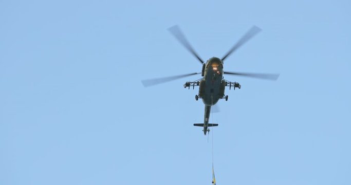 4K UHD slow motion video footage 60 fps. Military helicopter on battlefield flies overhead passing in blue skies and clouds at city. Military parade. War machine in the city. Slow-motion video.