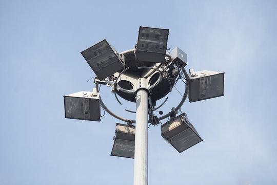 Lighting pole with halogen floodlight and  lightning conductor on the top of it. Metal construction with illuminator. Lighting coverage of a large area. City and urban illumination.
