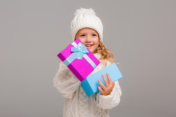 little blonde girl in winter white winter hat smiling holding a pink gift box