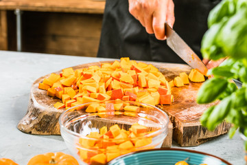 Chef cutting fresh and delicious pumkin and vegetables for cooking soup