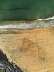 Aerial view on sandy beach and ocean surface with waves, Nature background. Yellow and turquoise color.