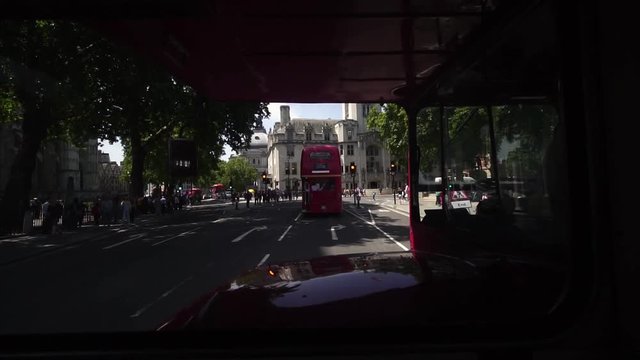 Riding historic double deck routemaster bus downtown London, black taxis and red buses on bridge near London Eye, Palace of Westminster, Houses of Parliament. 