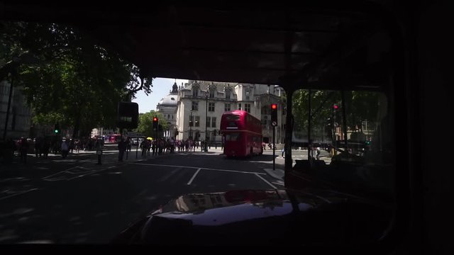Passenger pov double deck routemaster bus downtown London, black taxis and red buses on bridge near London Eye, Palace of Westminster, Houses of Parliament. 