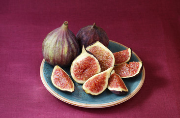 Figs on a plate on a bright purple background.
