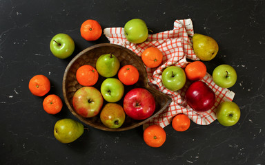 Fat lay photo - colourful fruits - apples, pears and tangerines on black marble like board