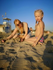Mom and kids play in the sand on the beach