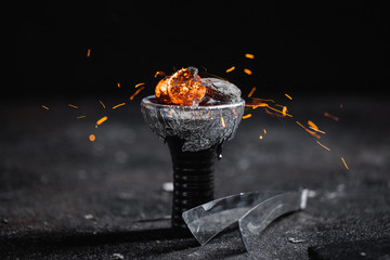 Hot coals in a shisha's bowl with spectacular red sparks, inox clamp. Dark textured background