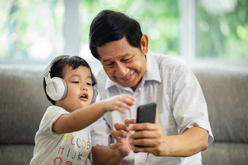 Happiness Asia grandfather  and grandson playing game in living room at home