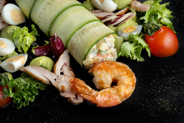 Plate with appetizers, shrimp, cucumber, eggs, salad.