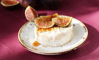 Baked Camembert cheese with figs on a bright purple background. Hard sunlight, deep shadow. sunny weather. fashion light, copy space