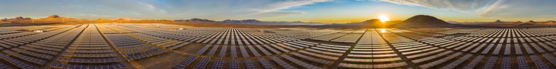 Aerial view of hundreds solar energy  panels rows along the dry lands at Atacama Desert, Chile. Huge Photovoltaic PV Plant in the middle of the desert from an aerial drone point of view during sunset
