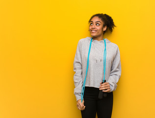 Young fitness black woman dreaming of achieving goals and purposes. Holding a jump rope.