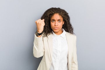 Young african american business woman showing fist to camera, aggressive facial expression.