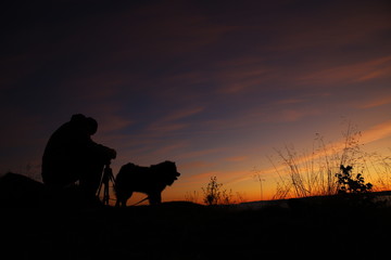 Fototapeta na wymiar Silhouette of photographer and a dog