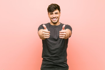 Young hispanic casual man with thumbs ups, cheers about something, support and respect concept.