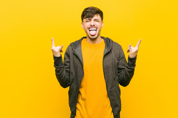 Young hispanic casual man showing rock gesture with fingers