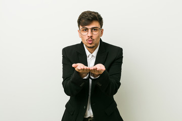 Young business hispanic man folding lips and holding palms to send air kiss.