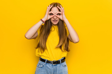 Naklejka premium Young ginger redhead woman showing okay sign over eyes