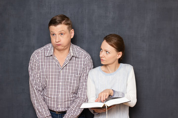 Woman is trying to pay attention of bored man to text in book