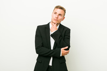 Young caucasian business man looking sideways with doubtful and skeptical expression.