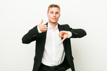 Young caucasian business man showing thumbs up and thumbs down, difficult choose concept