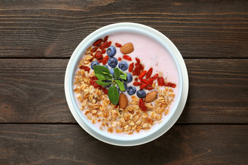 Smoothie bowl with goji berries on wooden table, top view