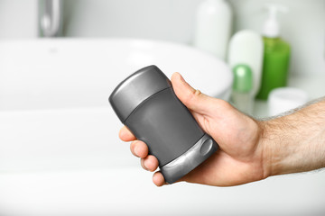 Man holding stick deodorant in bathroom, closeup view