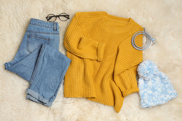 Set of stylish winter clothes on white faux fur, top view