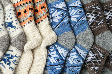 Different knitted woolen socks as background, top view