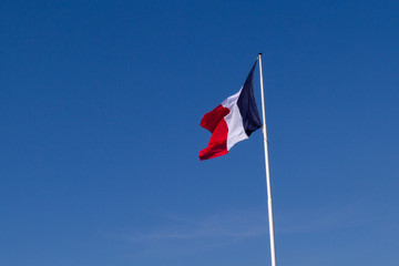 A fluttering French flag against the sky. Shot at the Necropolis of Notre-Dame-de-Lorette, memorial of the WW I (1914-1918).