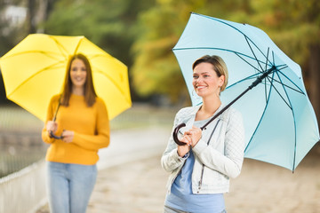 Young women with umbrella in park in autumn