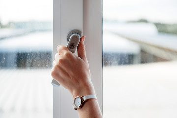 Woman hand closing new modern triple chamber home office window