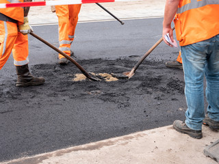 Group of people workers wearing special protection and safety orange costumes posing asphalt in Dutch city central square street