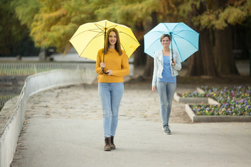 Two young women with umbrella in park