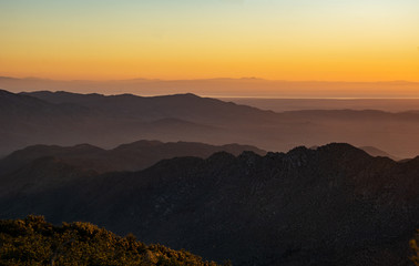 Desert and mountains seen from a distance at dawn with yellow sky and sunrise 