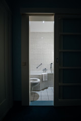 View of modern bathroom with bathtub, toilet bowl and water shower tap and white towel hanged on corner