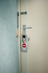 Modern hotel room door with do not disturb warning sign on door knob