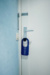 Modern hotel room door with please make up my room blue warning sign on door knob