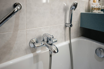 View of modern bathroom with bathtub detail and chrome water shower tap