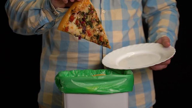 Man scraping with a plate a pizza into garbage bin