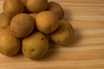 Fresh and raw potatoes stacked on wooden table, copy space and text. Rustic Style..
