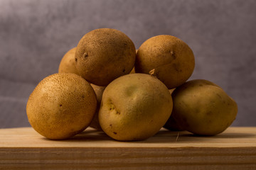 Fresh and raw potatoes stacked on wooden table, copy space and text. Rustic Style..