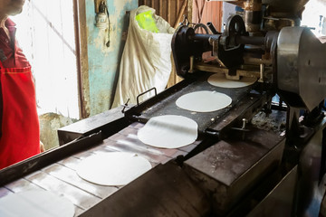 Fototapeta na wymiar Las tortillas de maíz se están haciendo en la maquina.